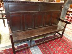 AN 18th C. OAK SETTLE WITH SEVEN PANEL BACK, SOLID SEAT AND SQUARE SECTIONED LEGS, THE FRONT