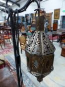 AN 19th CENTURY EASTERN STYLE BRASS LANTERN SUSPENDED AS A STANDARD LAMP FROM AND ADJUSTABLE ON AN