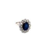 AN OVAL SAPPHIRE AND DIAMOND CLUSTER RING. THE SAPPHIRE MEASURES APPROX 12 x 10 x DEPTH 6.3mm.
