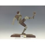 AN ART DECO CHROME FOOTBALLER DETAILED IN BLACK KICKING UP THE BALL WITH ONE FOOT RAISED, THE BASE