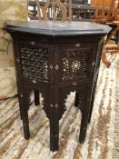 AN ISLAMIC OCTAGONAL TABLE, THE FOLIATE SCROLL CARVED TOP INSET WITH CENTRAL MOTHER OF PEARL AND