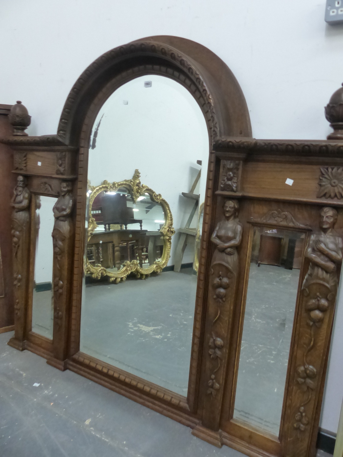 A VICTORIAN TRIPLE PLATE BEVELLED GLASS MIRROR, THE CENTRAL ROUND ARCH OF THE OAK FRAME FLANKED BY