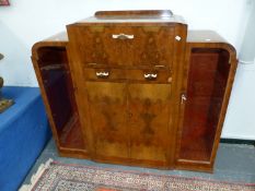 AN ART DECO WALNUT DRINKS CABINET, THE CENTRALLY DOMED TOP OPENING TO REVEAL PINK MIRRORED GLASS