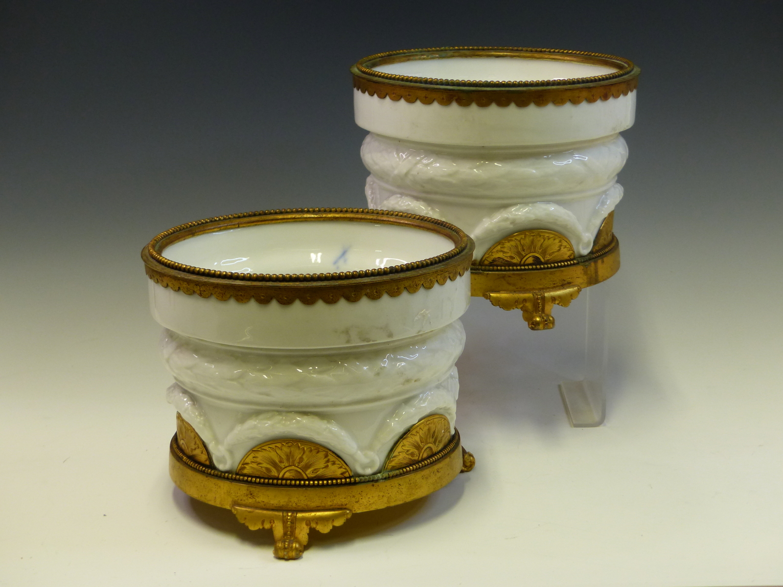 A PAIR OF GERMAN WHITE PORCELAIN PLANTERS, THE TRIPOD BASES AND BEADED RIMS IN ORMOLU. Dia. 19 x H