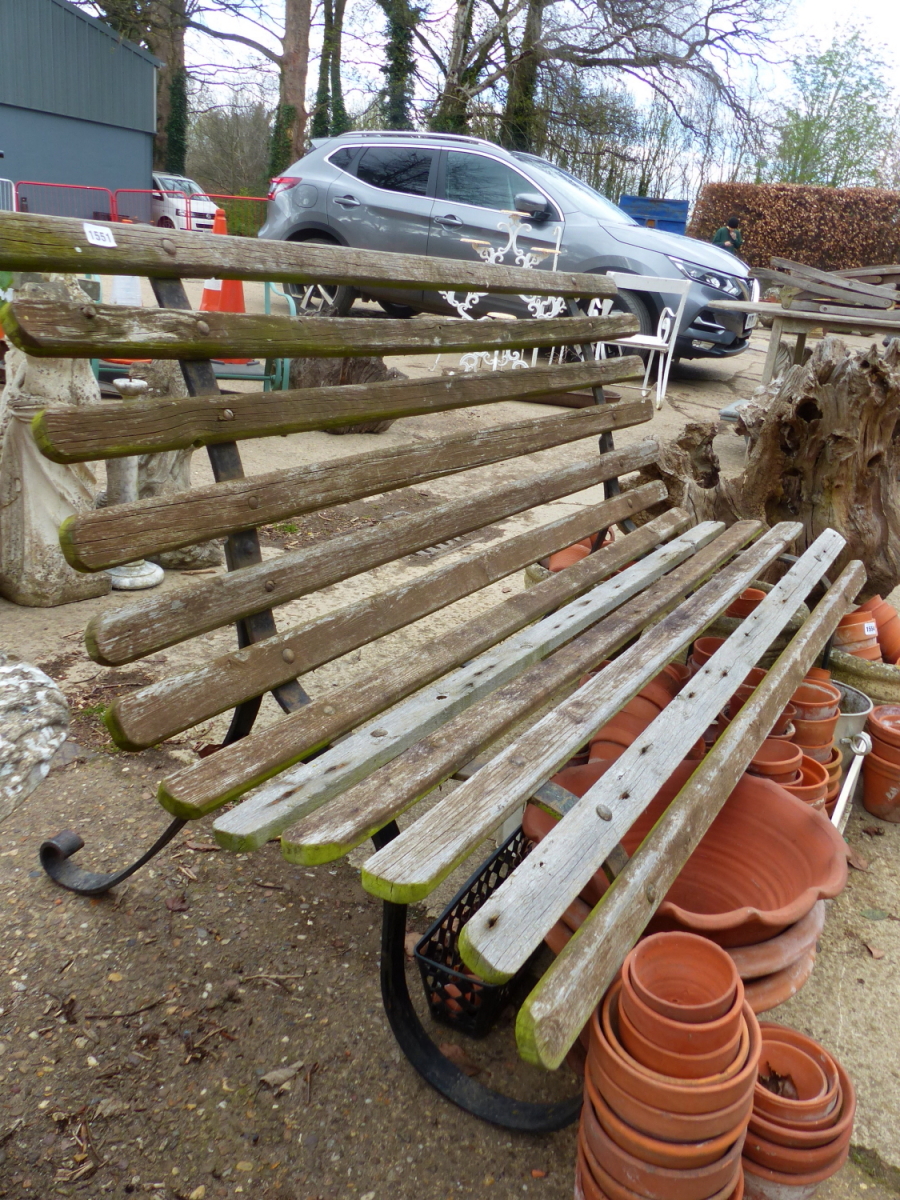 A TEAK SLATTED GARDEN BENCH WITH WROUGHT IRON SUPPORTS. H 90 x W 153 x D 85cms