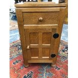 A ROBERT MOUSEMAN THOMPSON OAK BEDSIDE CUPBOARD WITH A DRAWER OVER A FOUR PANELLED DOOR ABOVE