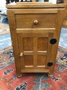 A ROBERT MOUSEMAN THOMPSON OAK BEDSIDE CUPBOARD WITH A DRAWER OVER A FOUR PANELLED DOOR ABOVE