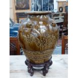 A MARTABAN BROWN GLAZED STONEWARE STORAGE JAR AND WOOD STAND, THE OVOID BODY WITH FIVE LIONS HEADS