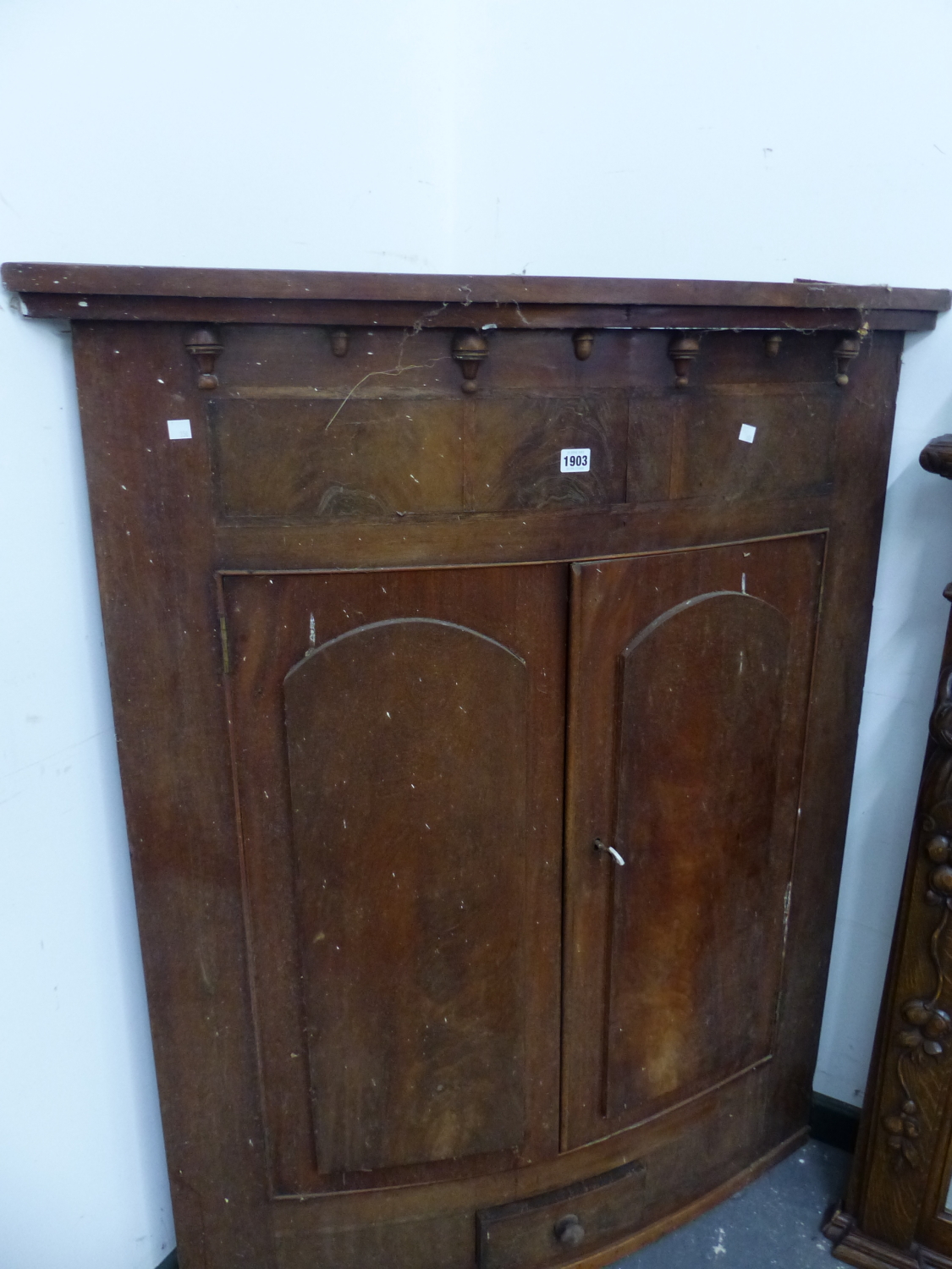 A GEORGE III MAHOGANY BOW FRONT CORNER CUPBOARD, THE ROUND ARCH PANELLED DOORS ABOVE A SMALL DRAWER.