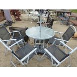 A MODERN GLASS TOP PATIO TABLE WITH A PARASOL AND FOUR MATCHING CHAIRS AND A PAIR OF SIMILAR SUN