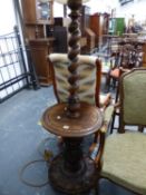 AN OAK SPIRAL TWIST STANDARD LAMP, THE COLUMN ABOVE A CIRCULAR TABLE TOP ON A FOLIATE CARVED