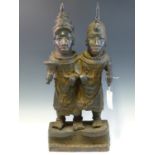 A LATE 19th C. BRONZE OF TWO BROTHERS STANDING ARM IN ARM ON A PLINTH, HE ON THE LEFT A VILLAGE