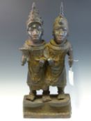 A LATE 19th C. BRONZE OF TWO BROTHERS STANDING ARM IN ARM ON A PLINTH, HE ON THE LEFT A VILLAGE