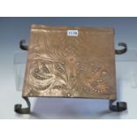 AN ARTS AND CRAFTS COPPER TRIVET, POSSIBLY BY C R ASHBEE, THE TOP WORKED WITH A FLORAL DESIGN