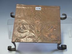 AN ARTS AND CRAFTS COPPER TRIVET, POSSIBLY BY C R ASHBEE, THE TOP WORKED WITH A FLORAL DESIGN