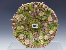 A STUDIO POTTERY DISH APPLIED WITH COLOURED STRAWBERRY FLOWERS ON A BROWN BASKET WORK EIGHT PANEL