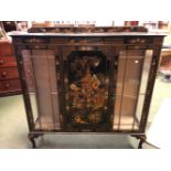 A 1920S BLACK LACQUER GROUND CHINOISERIE THREE DOOR DISPLAY CABINET DECORATED WITH ISLAND SCENES,