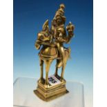 A 19th C. INDIAN POLISHED BRASS FIGURE OF SHIVA HOLDING HIS ATTRIBUTES IN HIS FOUR HANDS AS HE RIDES
