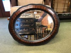 AN EARLY 20TH CENTURY OVAL WALL MIRROR IN WOOD EFFECT GESSO FRAME.