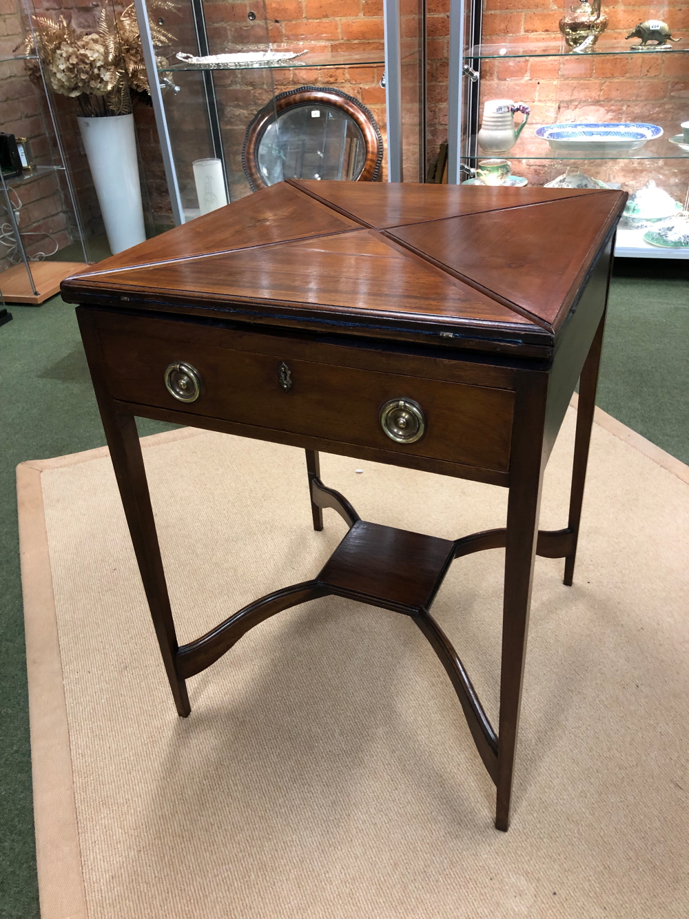 AN EDWARDIAN MAHOGANY ENVELOPE OPENING CARD OR GAMES TABLE, THE FOUR FLAP TOP OPENING TO REVEAL A