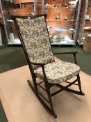 A 20th C. STAINED WOOD ROCKING ARMCHAIR WITH CUSHIONED STICK BACK AND DROP IN SEAT.
