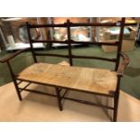 A 20th C. ARTS AND CRAFTS STAINED WOOD TWIN BAR BACK RUSH SEATED SETTEE. W 120cms.