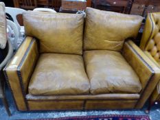 A TWO SEAT SETTEE CLOSE NAIL UPHOLSTERED IN BROWN LEATHER. W 140 x D 100 x H 85cms.