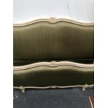 A CREAM PAINTED DOUBLE BED, THE ENDS WITH DOUBLE FLOWER CENTRED TOPS AND UPHOLSTERED IN OLIVE