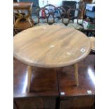 AN ERCOL TEAK FLAP TOP COFFEE TABLE, THE CIRCULAR TOP OPENING ON A SINGLE GATE. Dia. 61 x H 35.5cms.