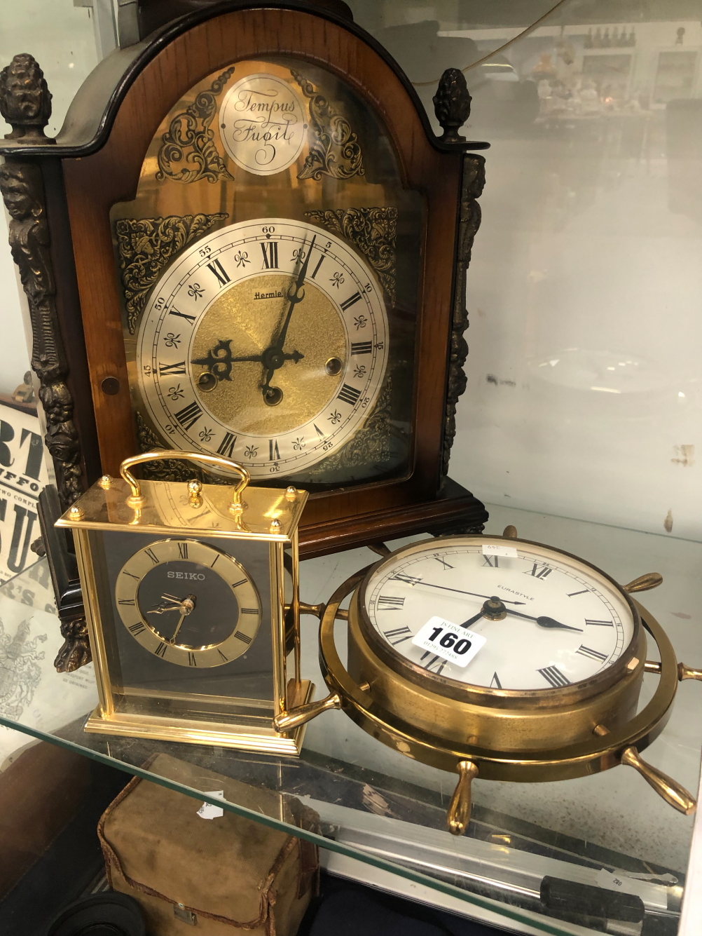 A 20th C. MANTLE CLOCK, A SEIKO CLOCK AND A SHIPS WHEEL CASED WALL CLOCK