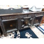 AN 18th C. OAK COFFER, THE THREE PANELS TO THE FRONT FRAMED BY FEATHER CARVING AND CENTRED BY