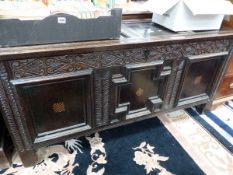 AN 18th C. OAK COFFER, THE THREE PANELS TO THE FRONT FRAMED BY FEATHER CARVING AND CENTRED BY