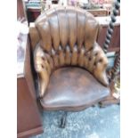 A 20th C. DESK CHAIR CLOSE NAILED AND BUTTON UPHOLSTERED IN BROWN LEATHER AND ROTATING ON