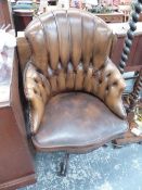 A 20th C. DESK CHAIR CLOSE NAILED AND BUTTON UPHOLSTERED IN BROWN LEATHER AND ROTATING ON