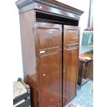 A 20th C. MAHOGANY WARD ROBE, THE DENTIL CORNICE OVER TWO PANELLED DOORS ENCLOSING SLIDES AND TWO