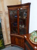 A 20th C. MAHOGANY CORNER CUPBOARD, THE INCURVED FRONT GLAZED ON THE UPPER HALF AND PANELLED ON