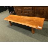 A RUSTIC HARDWOOD PIG BENCH COFFEE TABLE.