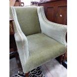 A VICTORIAN ARMCHAIR UPHOLSTERED IN OLIVE GREEN VELVET, THE MAHOGANY LEGS ON CERAMIC CASTER FEET