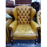 A WING ARMCHAIR BUTTON BACK UPHOLSTERED IN HONEY BROWN LEATHER