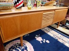 A 1970S TEAK SIDEBOARD WITH THE THREE CENTRAL DRAWERS FLANKED BY PULL DOWN CUPBOARDS. W 209 x D 45 x