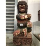 AN INDO-BURMESE WOODEN SEATED DEITY GRIMACING TO SHOW PROMINENT EYE TEETH. H 42cms.