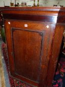 A GEORGE III OAK CORNER CUPBOARD, THE DOOR CENTRED BY A VASE OF FLOWERS OVAL WITHIN MAHOGANY CROSS