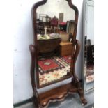 A VICTORIAN MAHOGANY FULL LENGTH CHEVAL MIRROR, THE WAVY PLINTH ABOVE SCROLL FRONT LEGS ON CASTER