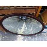 AN OVAL MIRROR IN A MAHOGANY FRAME. 56.5 x 70cms.