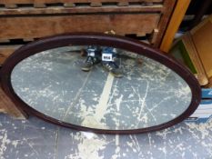 AN OVAL MIRROR IN A MAHOGANY FRAME. 56.5 x 70cms.