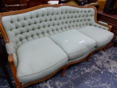 A BEECH SHOW FRAME SETTEE, THE BUTTONED BACK CENTRED BY A PAIR OF CARVED FLOWERS, THE THREE