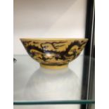 A CHINESE BOWL INCISED AND PAINTED WITH AUBERGINE DRAGONS ON A YELLOW GROUND, SIX CHARACTER MARK.