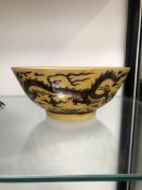 A CHINESE BOWL INCISED AND PAINTED WITH AUBERGINE DRAGONS ON A YELLOW GROUND, SIX CHARACTER MARK.