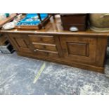 AN OAK DRESSER BASE WITH THE THREE CENTRAL DRAWERS FLANKED BY CUPBOARDS. W 176 x D 50 x H 66cms.