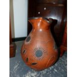 A TERRACOTTA JUG DECORATED WITH BLACK CENTRED FLOWERS. H 45cms